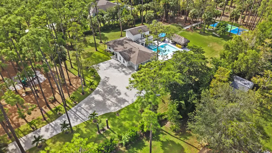 Aerial of the wooded 2.5-acre estate with long driveway, pool and sport court, The Naples Retreat, Naples FL