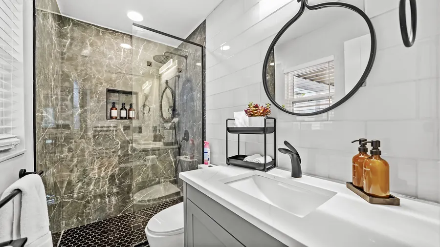 Guest bath with marble walk-in glass shower and round mirror, The Naples Retreat, Naples FL