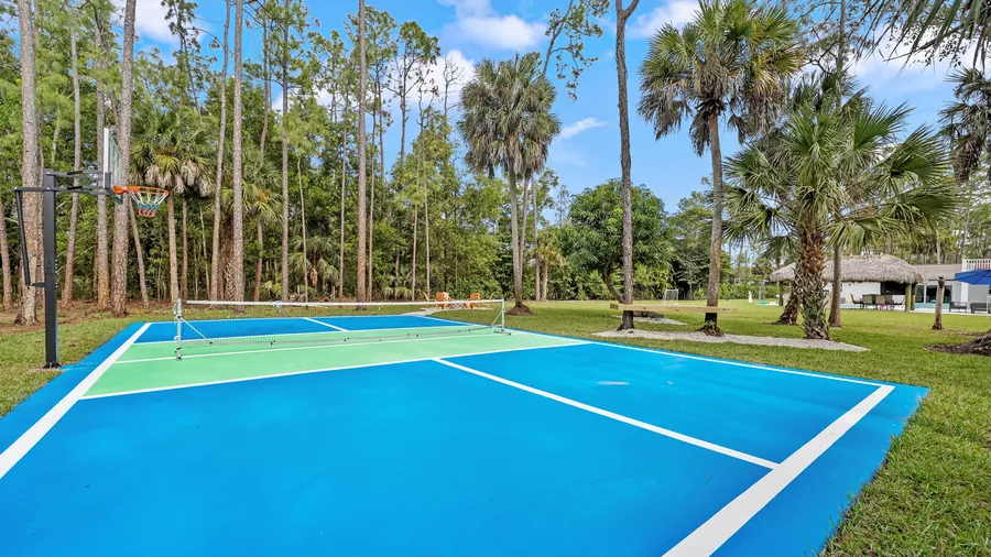 Blue and green pickleball court set among tall Florida pines, The Naples Retreat, Naples FL