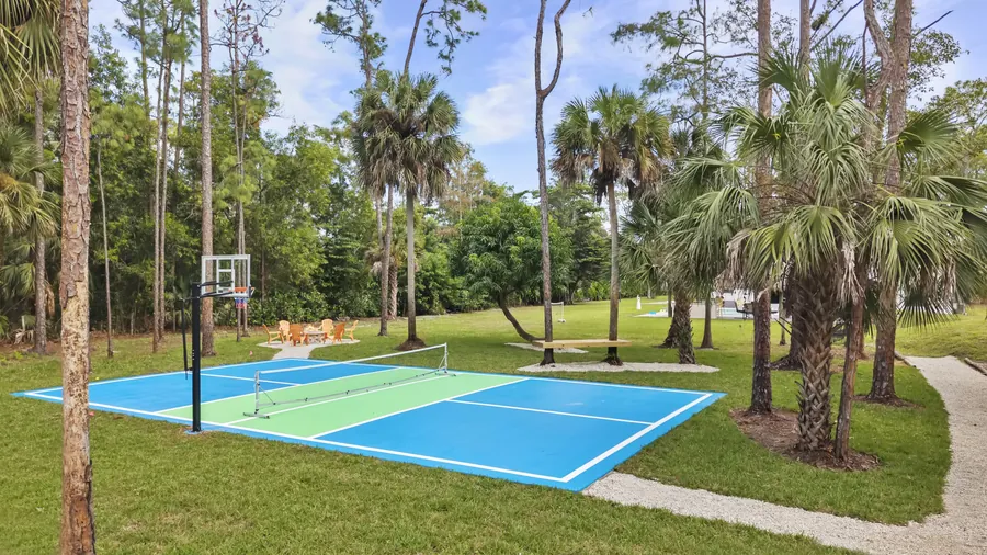 Full-size pickleball court with basketball hoop surrounded by palms and pines, The Naples Retreat, Naples FL