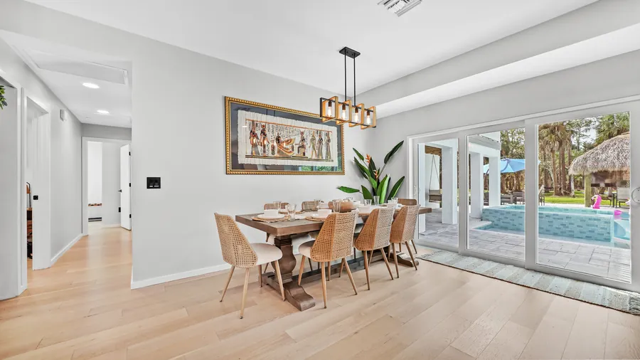 Dining table for ten under a gold chandelier with sliders to the pool, The Naples Retreat, Naples FL