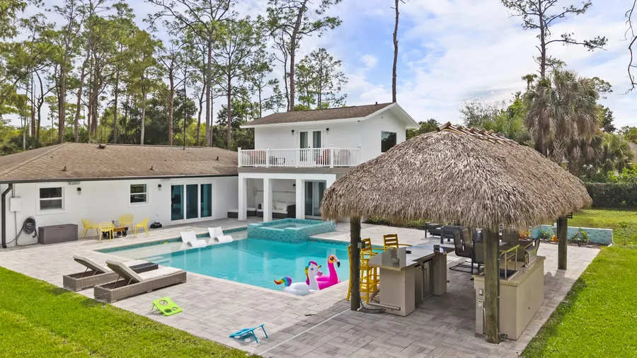 Saltwater pool, raised spa and thatched tiki bar behind the two-story home, The Naples Retreat, Naples FL