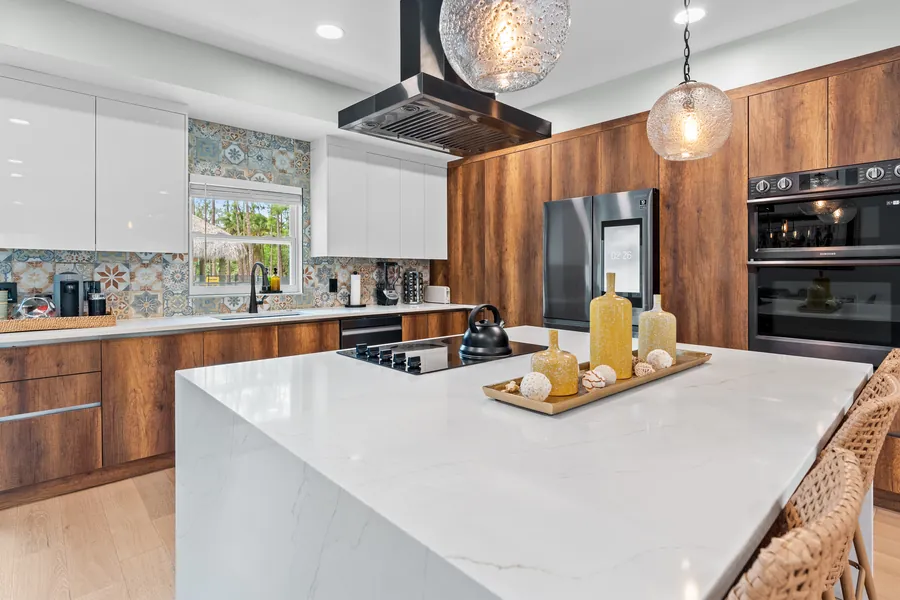 Kitchen with wood and white cabinetry, patterned tile backsplash and double ovens, The Naples Retreat, Naples FL
