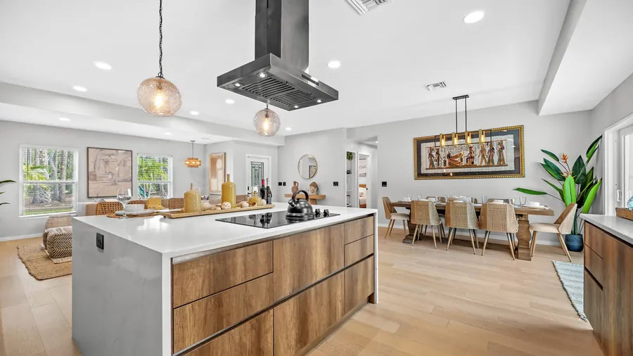 Waterfall-quartz kitchen island with cooktop, pendants and dining room beyond, The Naples Retreat, Naples FL