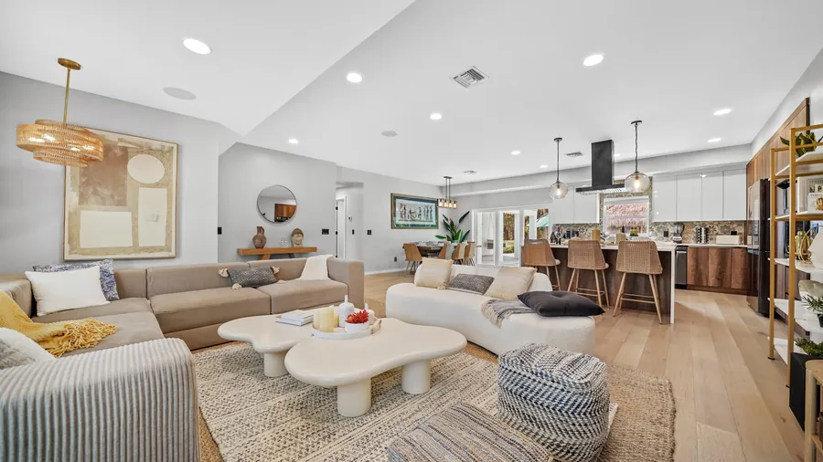Open living room with sectional, sculptural coffee tables and view to kitchen, The Naples Retreat, Naples FL