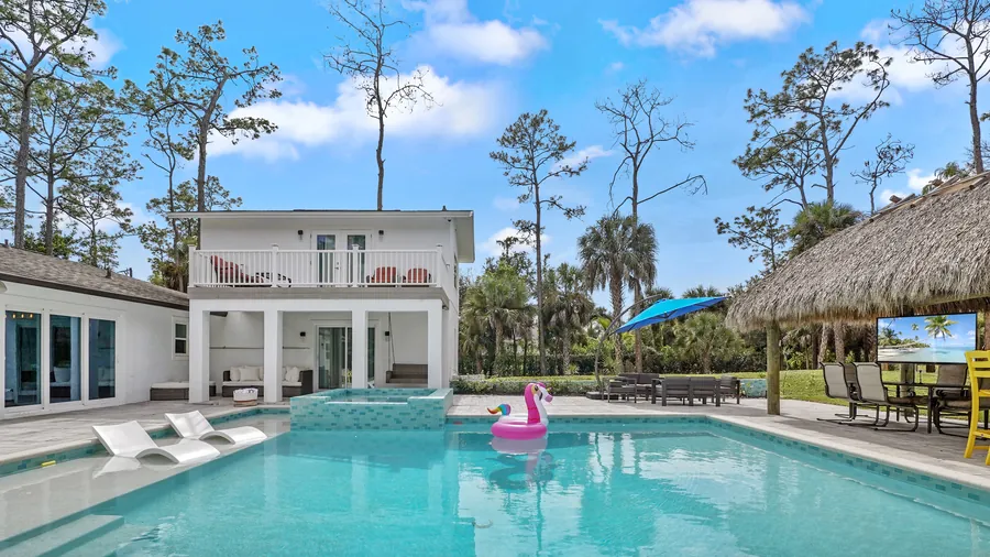 Saltwater pool with sun-shelf loungers and raised spa facing the house and tiki, The Naples Retreat, Naples FL