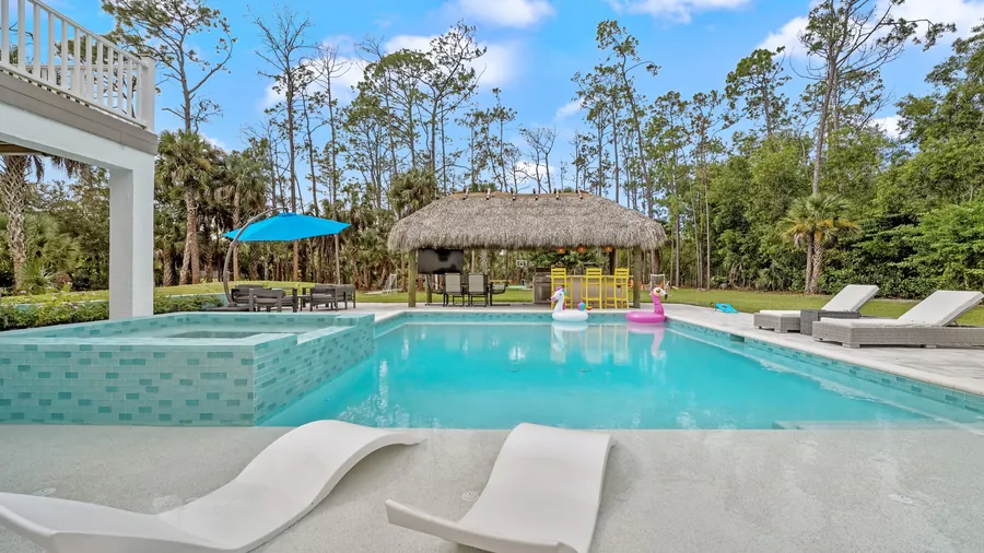 In-pool sun shelf loungers with raised spa and tiki hut beyond, The Naples Retreat, Naples FL
