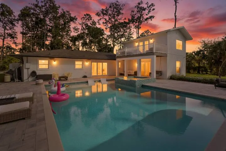 House and pool at dusk, lit from inside