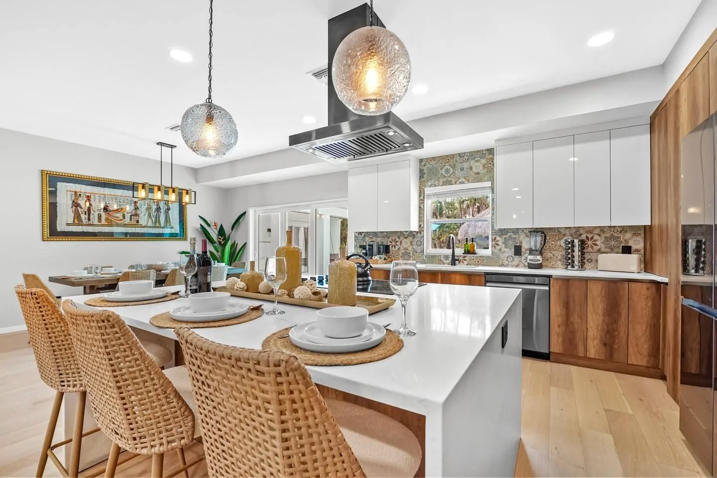 Kitchen island with rattan stools, pendant lights and wood cabinetry