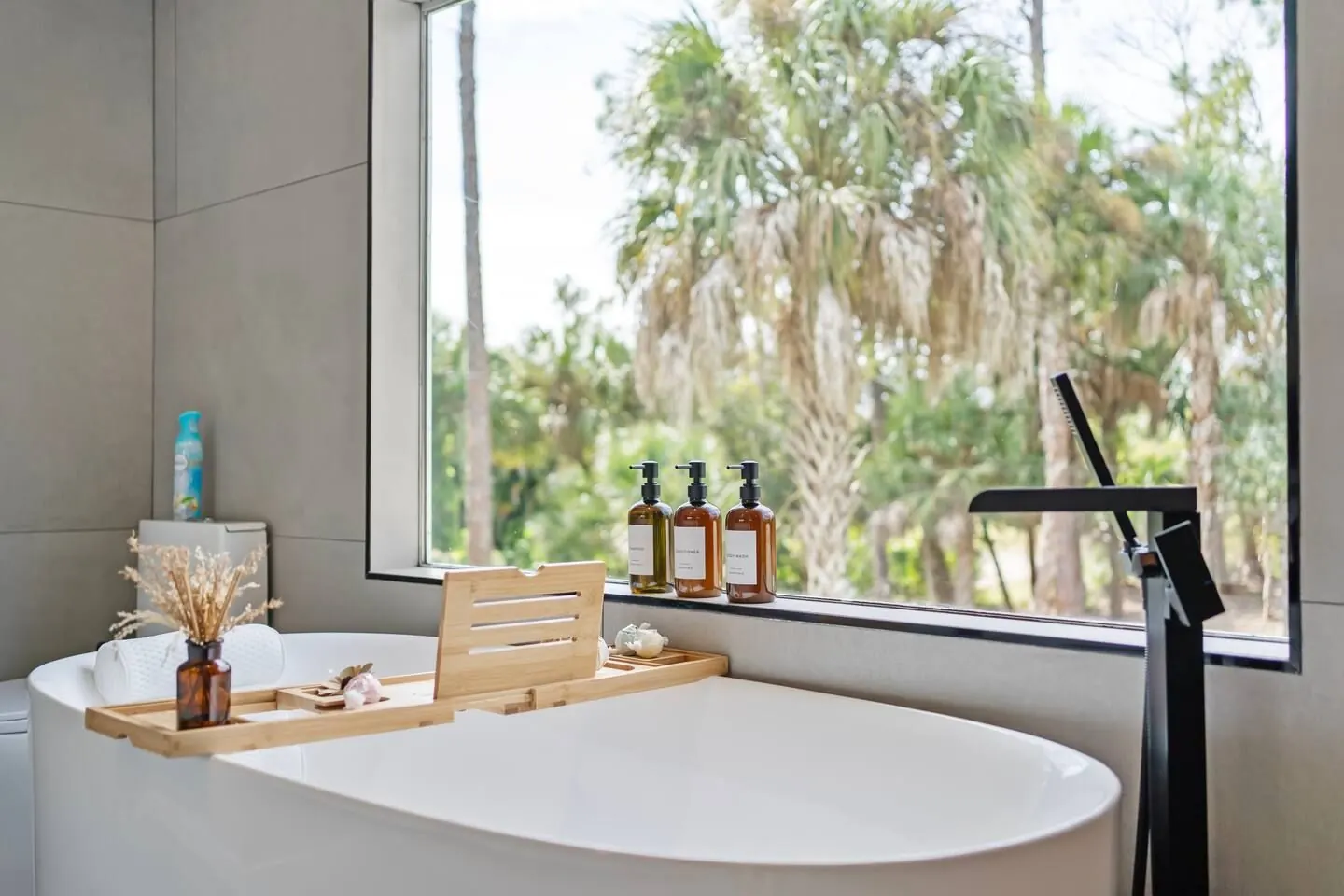 Freestanding soaking tub by a window onto the pines